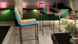 Uma área de estar moderna ao ar livre, com cadeiras de metal e uma piscina.