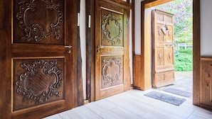 Une porte en bois ornée de sculptures complexes, un paillasson et un plancher en bois.