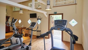 Une salle de sport à domicile équipée de tapis de course, d’un vélo d’exercice et d’une petite table avec une chaise.