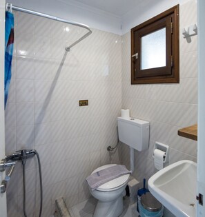 Ein Badezimmer mit Dusche, Toilette, Waschbecken und Fenster.