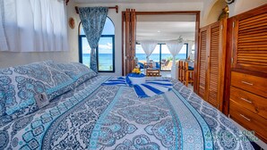 Un dormitorio con una cama grande, un armario de madera y vista a la playa.