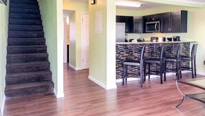 A modern kitchen with dark cabinets, a microwave, and a bar area with stools. - 5218 Beach Dr A (Panama City Beach)