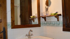 A bathroom with a white sink, a mirror, and a wooden door. - 2 bedroom apartment (Aliseda)