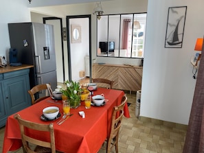 A compact kitchen with a dining area, featuring a refrigerator, coffee maker, and a table set with breakfast items.