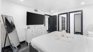 A modern hotel room with a large bed, a flat-screen TV, a dresser, and a mirror. - The Summit 132 (Panama City Beach)
