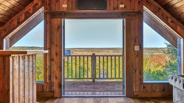A wooden interior with a large open door leading to a balcony.