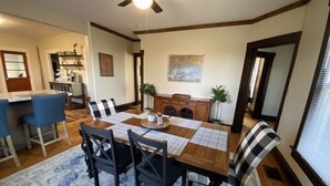 Un comedor con una mesa de madera, sillas azules y un mantel a cuadros.