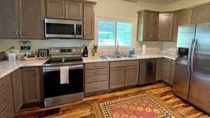 Una cocina con armarios de madera, un refrigerador de acero inoxidable, un microondas, un horno y un fregadero.