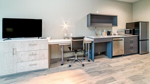Cocina moderna con televisor de pantalla plana, escritorio, silla, microondas y refrigerador.