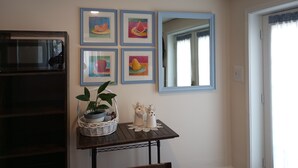 Ein Zimmer mit Esstisch, Mikrowelle, gerahmten Bildern, einem Spiegel und einer Topfpflanze.