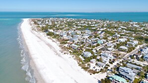 An aerial view of a coastal residential area with houses along the beach and a clear view of the ocean. - Paradise Bound! Backyard Bliss with Sun Shelf, BBQ and Coastal Decor (Anna Maria)