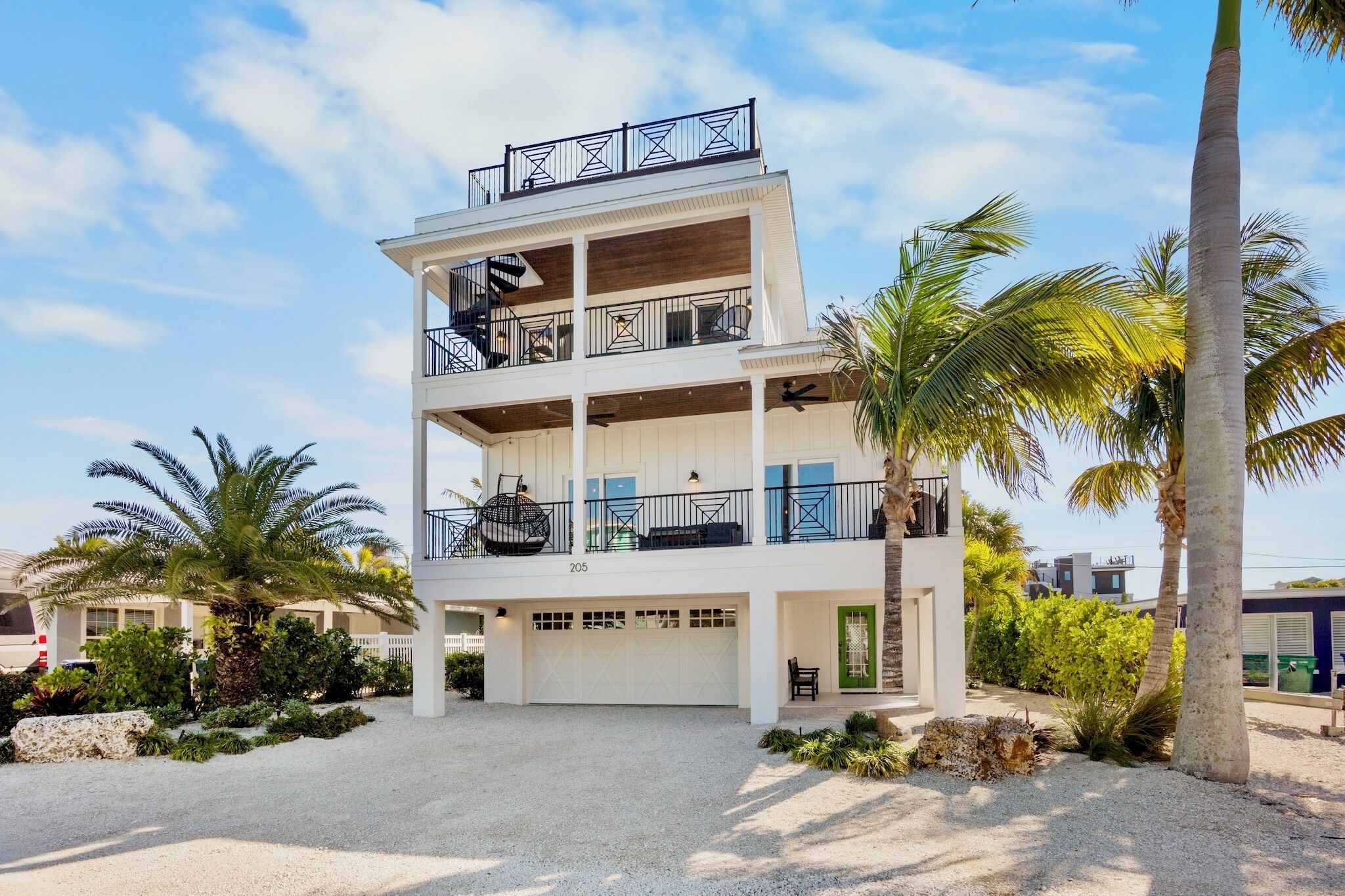 A multi-story building with a white exterior, balconies, and a garage.