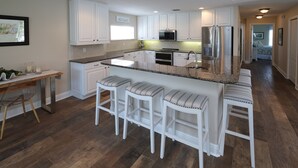 A modern kitchen with white cabinetry, granite countertops, and stainless steel appliances.