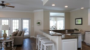 A modern kitchen with white cabinetry, a granite countertop, and a built-in island with bar stools.