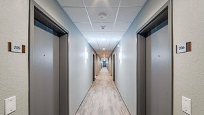 En hotellkorridor med två dörrar märkta 205 och 206, en upplyst nödutgångsskylt och ett trägolv.