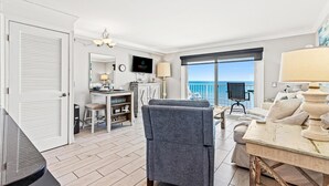 A spacious living room with a view of the sea, a dining area with a table and chairs, and a cozy seating area with a sofa and armchairs. - The Summit 1121 (Panama City Beach)