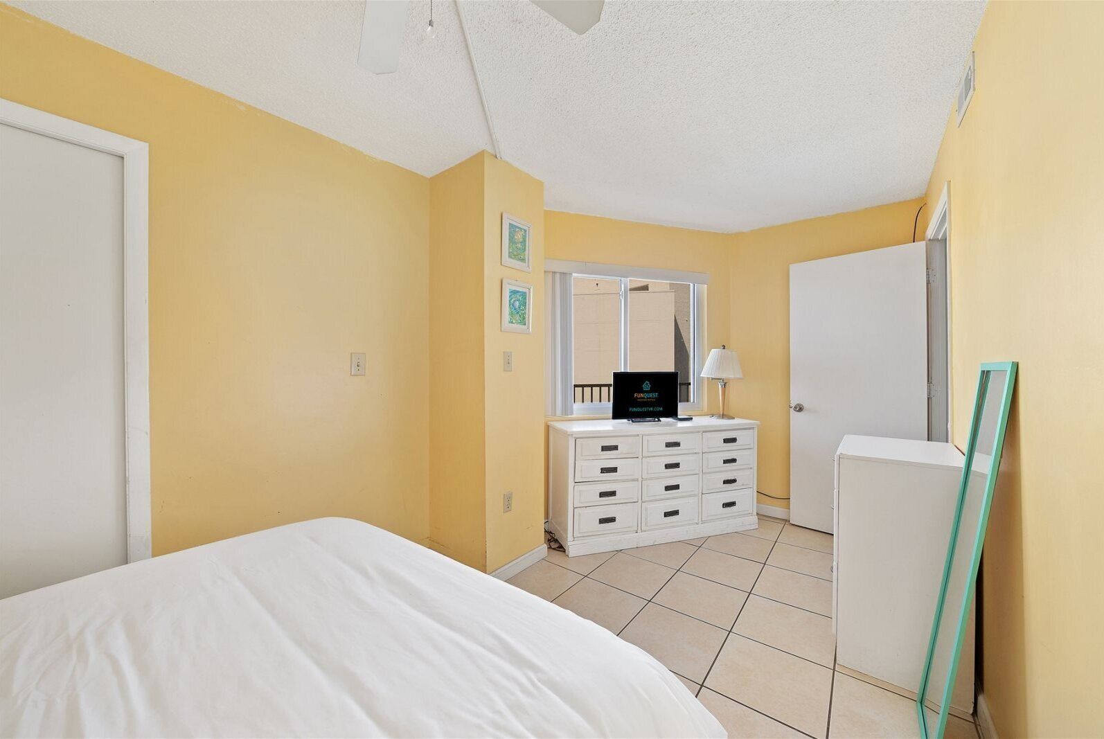 Une chambre à coucher avec un lit, une commode, un miroir et une porte.