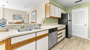 A modern kitchen with white cabinetry, a stainless steel dishwasher, and a black refrigerator.