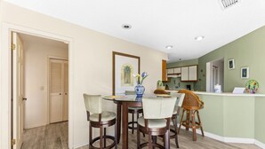 A dining area with a round table, four chairs, and a vase with flowers.