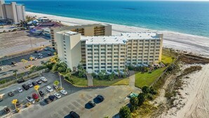 Un hôtel situé en bord de mer, avec plusieurs étages, un parking et une vue sur l’océan.