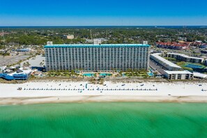 A large hotel with a central courtyard, multiple swimming pools, and a beach area with sun loungers. - The Summit 602 (Panama City Beach)