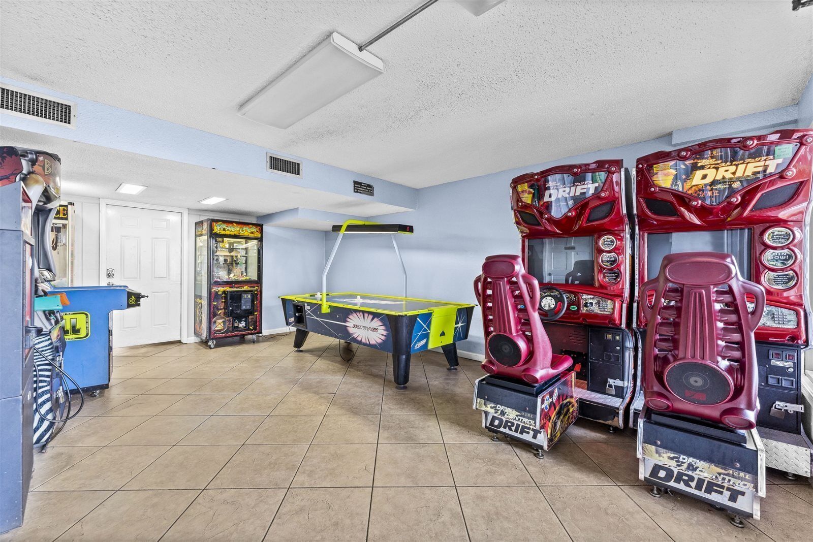 Una habitación con juegos de arcade, una mesa de billar y una puerta.