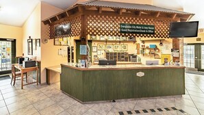 Un espace d’accueil avec un comptoir, des chaises et un panneau indiquant l’emplacement du bureau d’enregistrement et d’accueil du motel Everglades City et de l’établissement Ivy House.