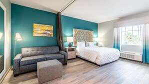 Une chambre moderne avec des murs de couleur turquoise, un grand lit, un canapé et une table de chevet avec des lampes.