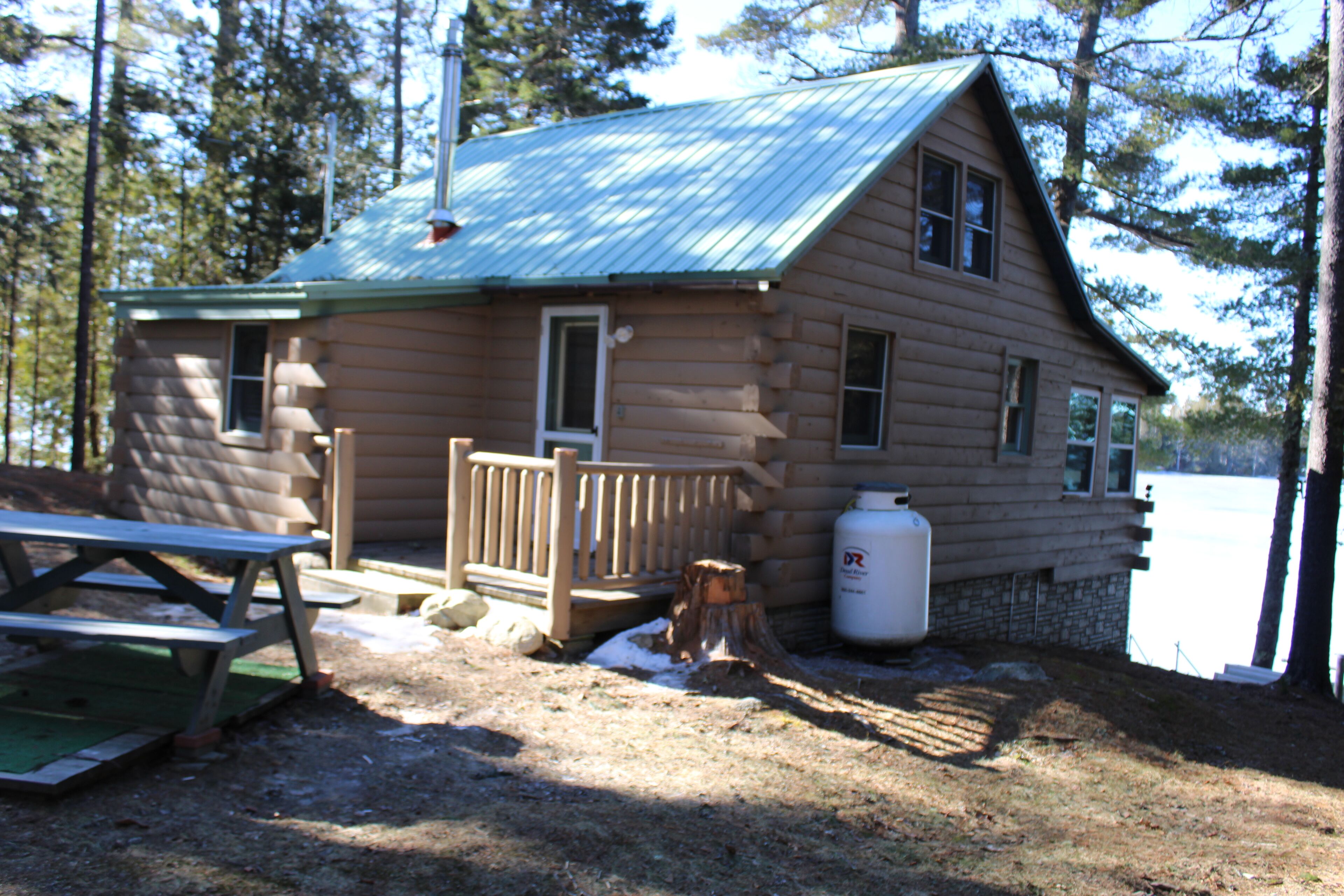A log cabin with a metal roof, a wooden deck, and a picnic table.