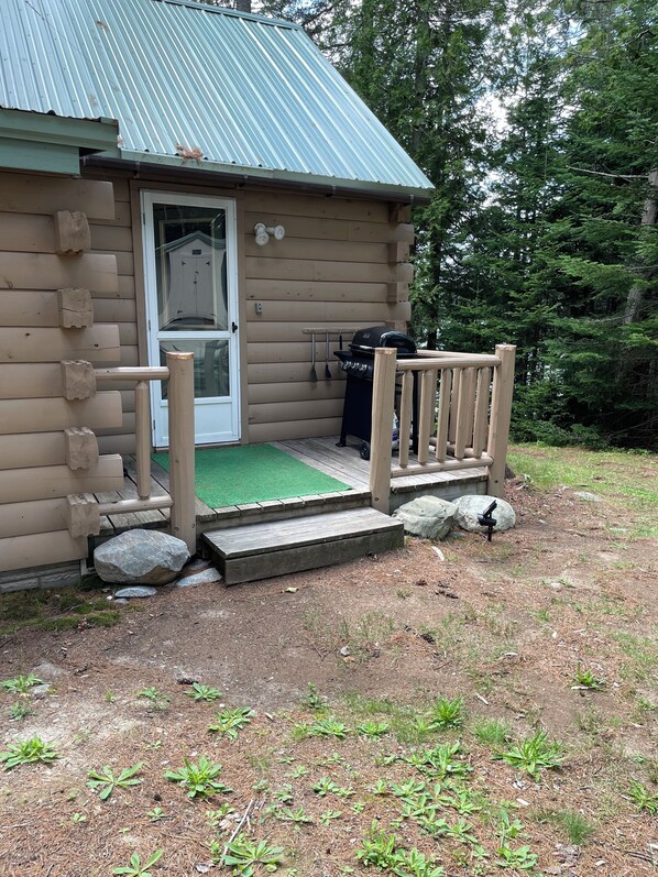 A log cabin with a wooden deck, a door, and a small porch with steps. - Lakefront Cabin near Acadia National Park (Franklin)