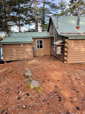 A cabin with a metal roof, a small window, and a chimney.