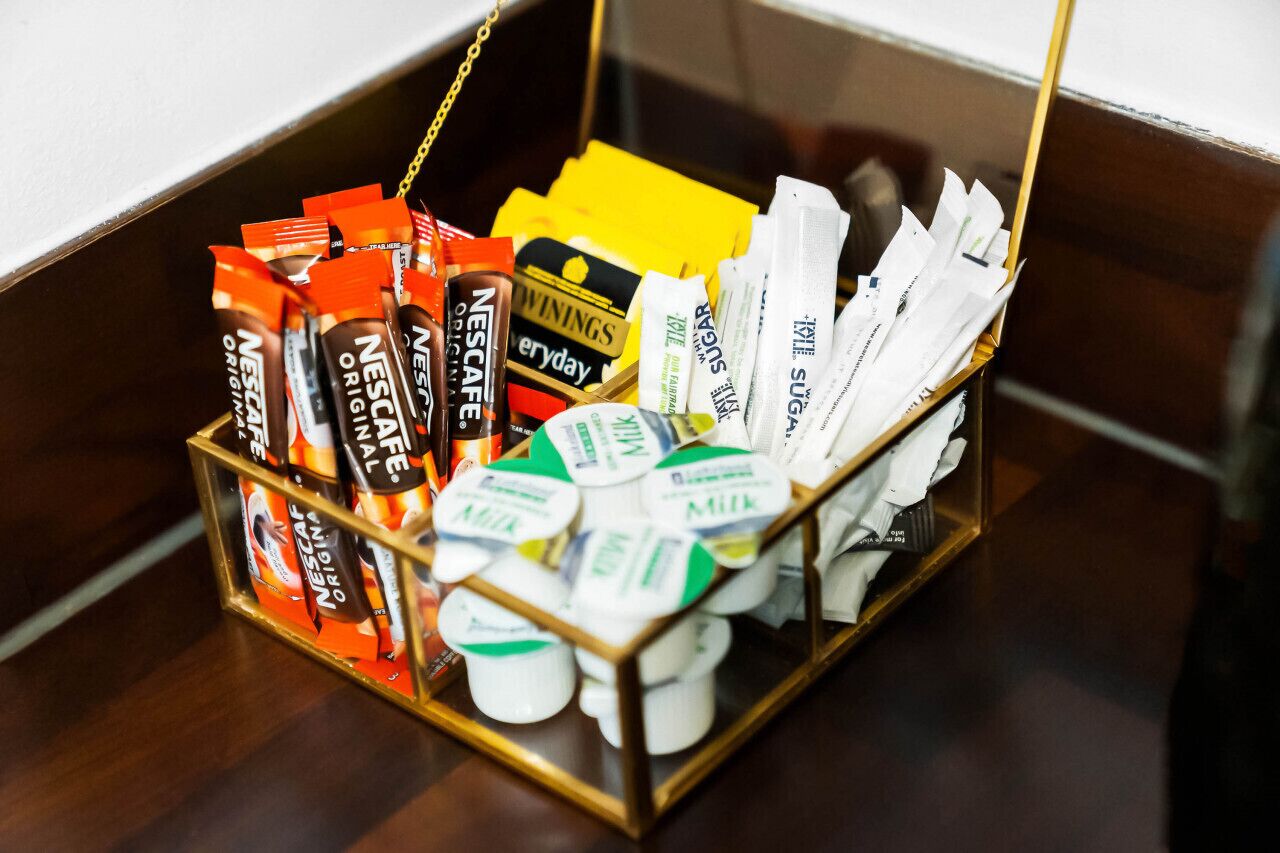 Kori, jossa on erilaisia elintarvikkeita, kuten Nescafé Original -kahvia, tavallista Nescafé-kahvia ja maitotölkkejä.