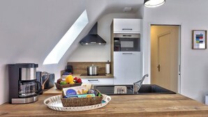 A modern kitchen with a coffee maker, a sink, and a countertop with a fruit basket. - 30 m2 terrace with sea view, 40 m from the beach and 300 m from shops (Guilvinec)