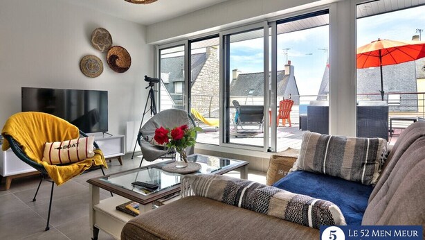A modern living room with a sofa, armchair, and a glass coffee table. - 30 m2 terrace with sea view, 40 m from the beach and 300 m from shops (Guilvinec)
