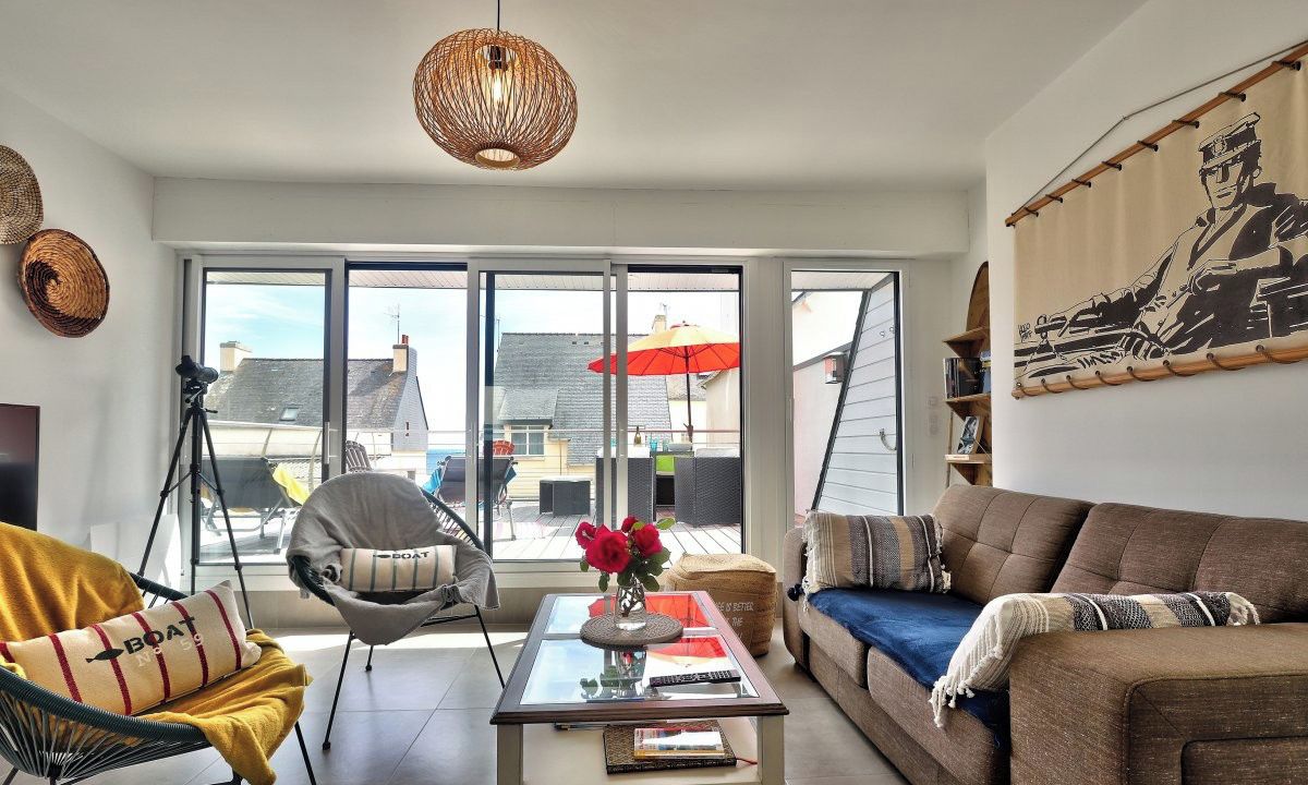 A modern living room with a glass coffee table, a sofa, a chair, and a large window with a view of the city.