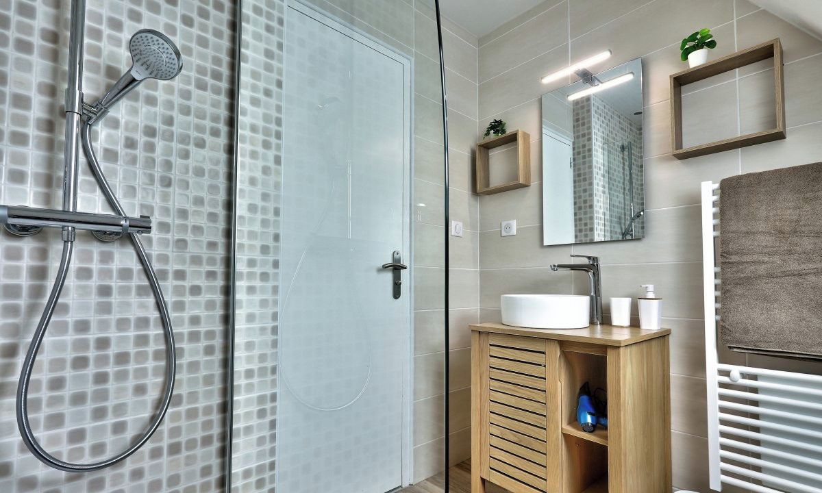 A modern bathroom with a glass shower enclosure, a wooden vanity, and a large mirror.