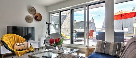 Un salon moderne avec un canapé, un fauteuil et une table basse en verre.
