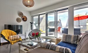 Un salon moderne avec un canapé, un fauteuil et une table basse en verre.