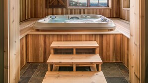 A wooden spa room with a hot tub, a window with a view, and a wooden bench. - Ski-in/Ski-out, In the Village, 7 King Bedrooms, 2 Bedrooms w/ 2 XL twins (Sandpoint)