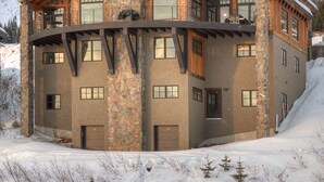 A multi-story log cabin with stone accents, large windows, and a snow-covered roof. - Ski-in/Ski-out, In the Village, 7 King Bedrooms, 2 Bedrooms w/ 2 XL twins (Sandpoint)