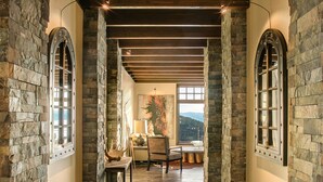 A hallway with stone walls, wooden beams, and a bench. - Ski-in/Ski-out, In the Village, 7 King Bedrooms, 2 Bedrooms w/ 2 XL twins (Sandpoint)