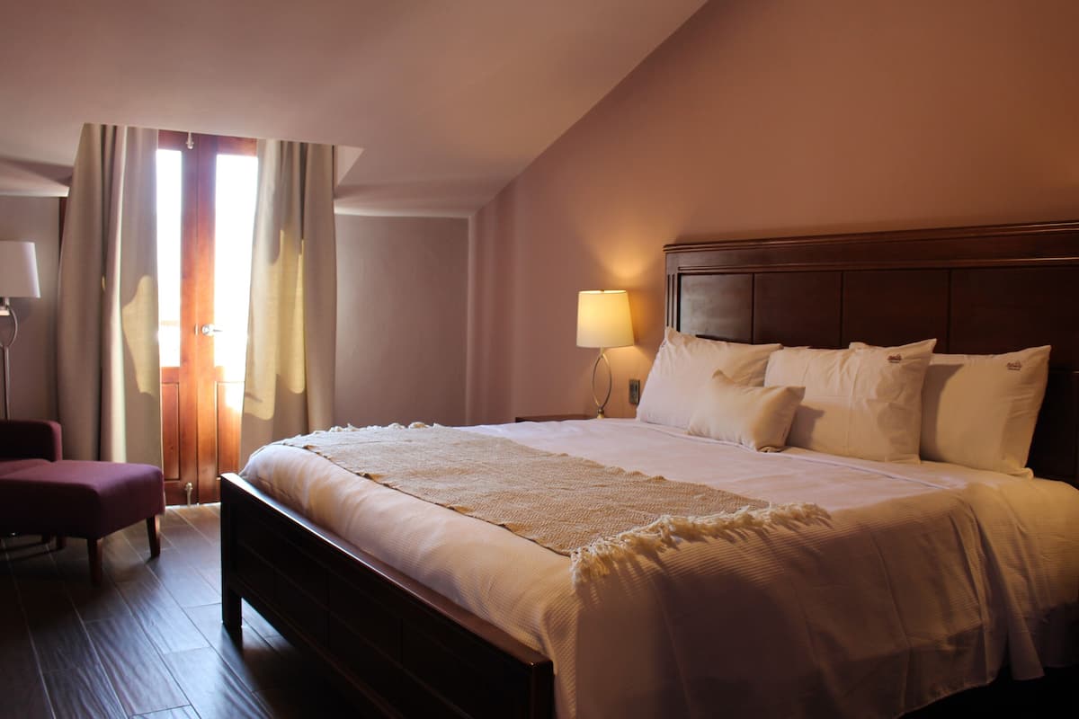 Une chambre d’hôtel avec un grand lit, une tête de lit en bois, une lampe de chevet et une chaise.