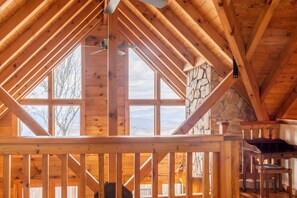 A wooden interior with a stone wall and large windows. - Long-range mtn views, huge deck, spa, play room, 1 mile to ski resort & trails (Beech Mountain)