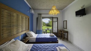 Ein Schlafzimmer mit zwei Betten, einem Schreibtisch, einem Fernseher und Blick ins Freie.