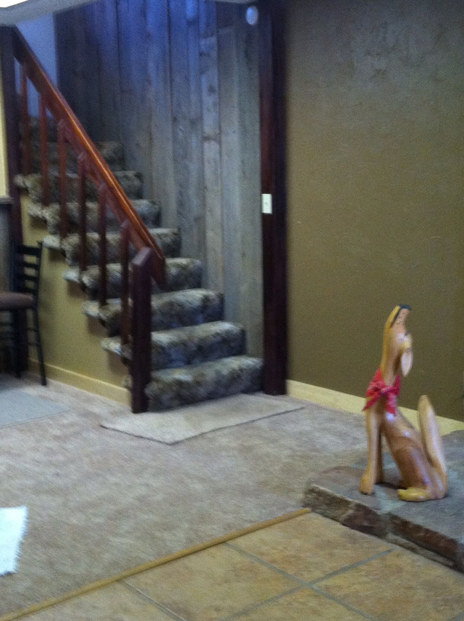 A staircase with wooden railings and stone steps, leading to a landing area with a tiled floor.