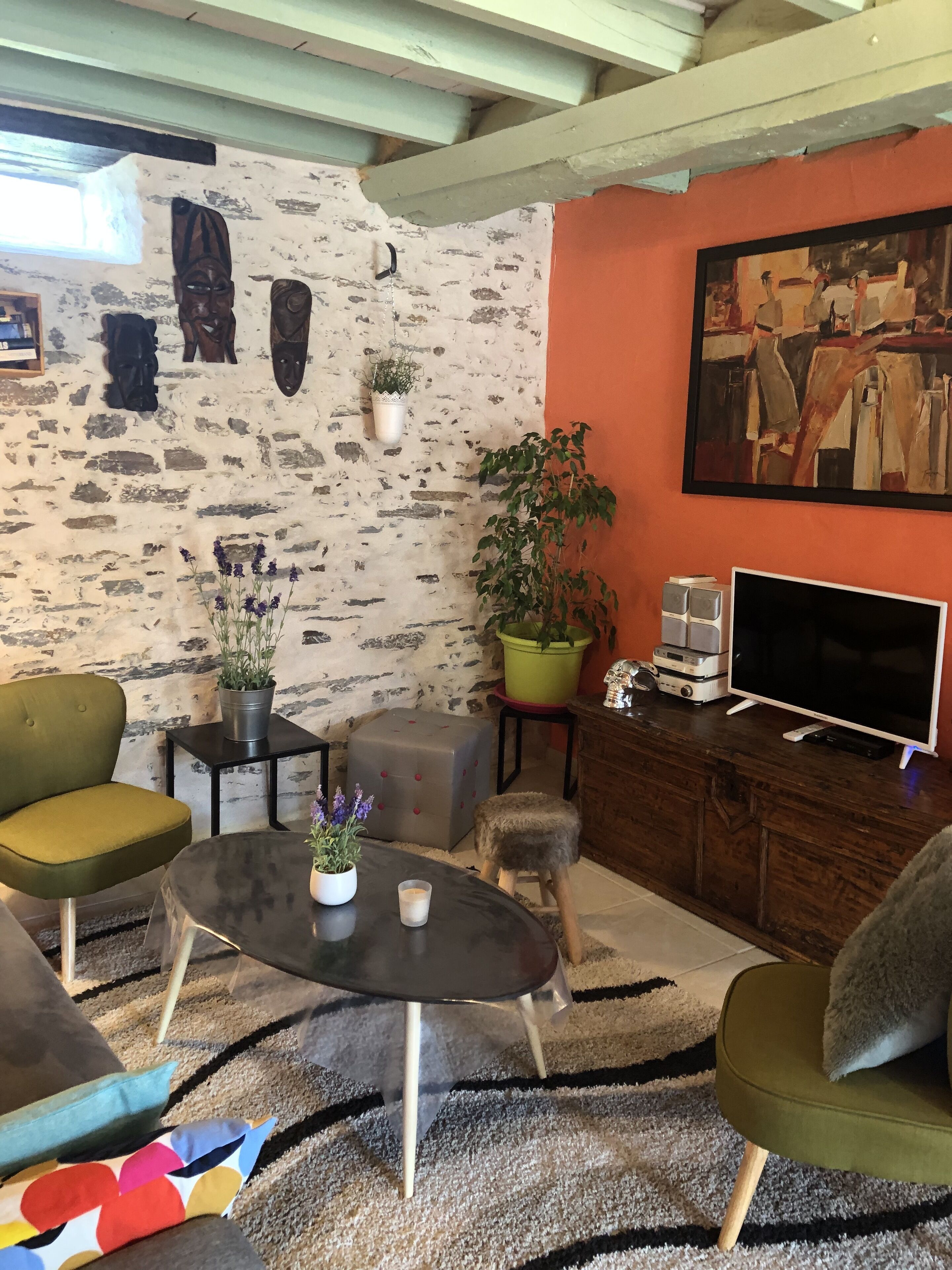 Een gezellige woonkamer met een stenen muur, een schilderij, een televisie en verschillende planten.
