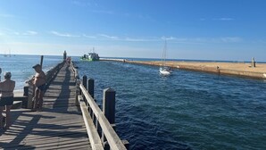 Une jetée en bois s’étendant dans des eaux calmes, sous un ciel dégagé.
