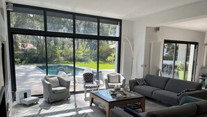 Un vaste salon doté d’une grande porte vitrée donnant accès à un espace piscine.