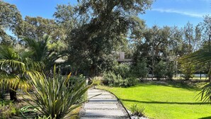 Un sentier de jardin bordé de pierres plates, entouré d’une végétation luxuriante et d’arbres.