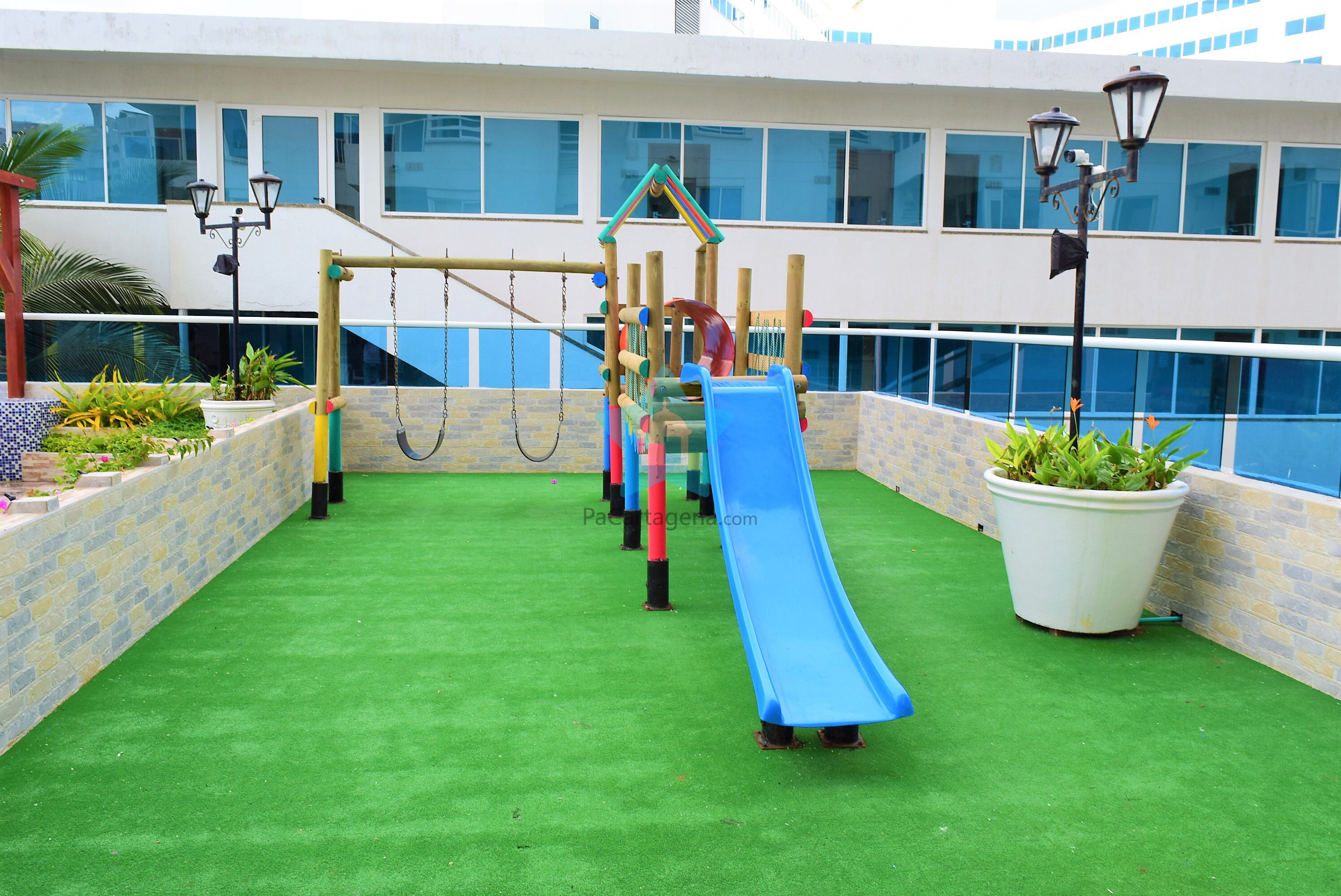 Uma área de recreação ao ar livre com escorrega, balanços e estruturas de escalada.